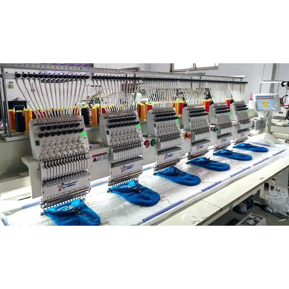 Multi-head embroidery machine stitching designs onto blue knit beanies