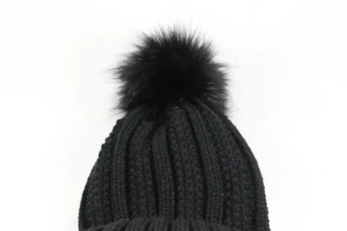 Close view of a dark ribbed knit beanie shell and black pom-pom