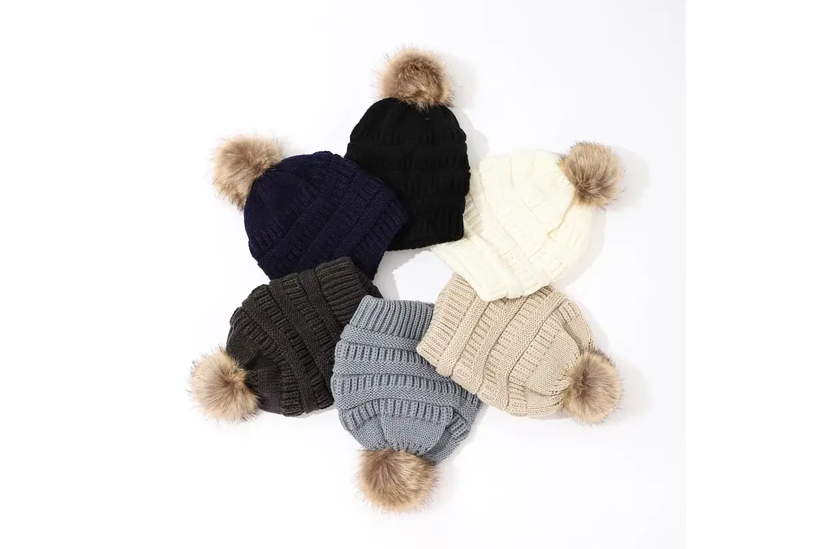 Six knit beanies in dark, cream and gray colors with tan faux fur poms