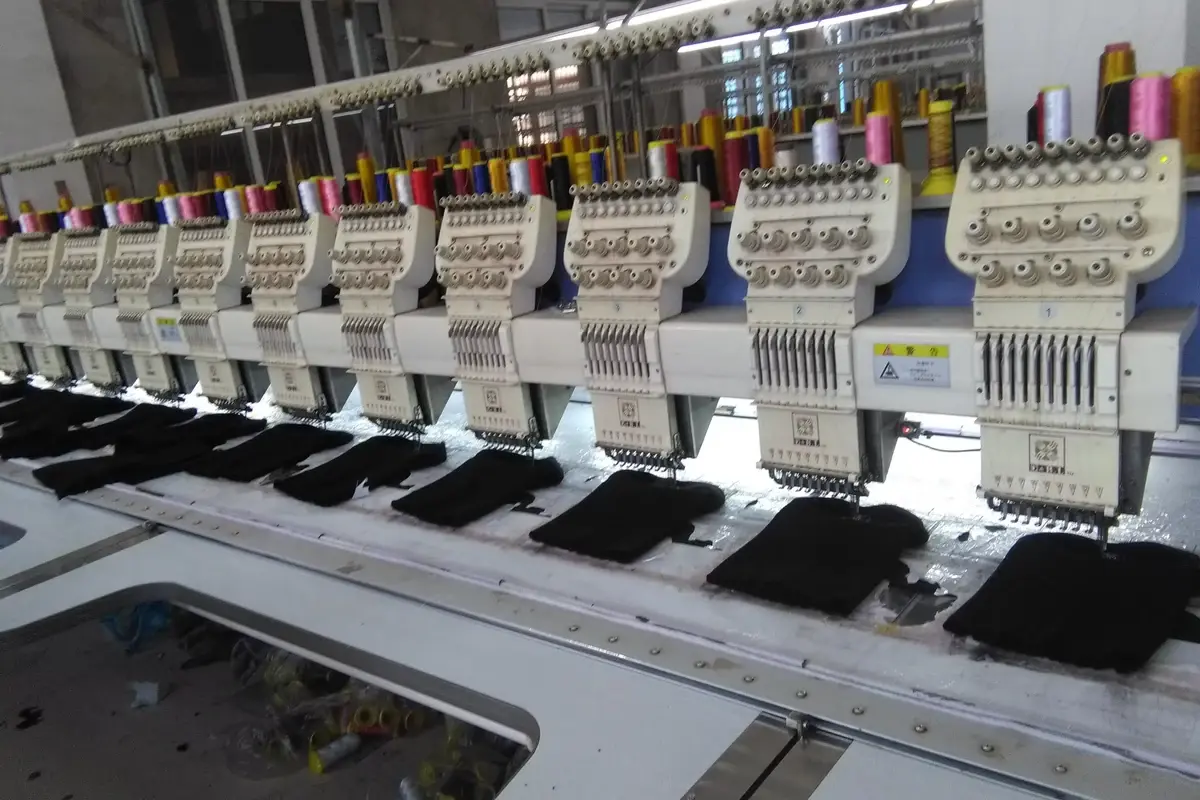 Rows of embroidery machines working on dark knit pieces