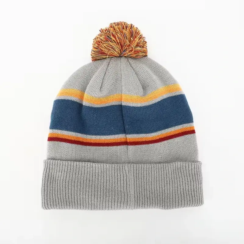Gray beanie with navy, red, and orange bands and a tan pom