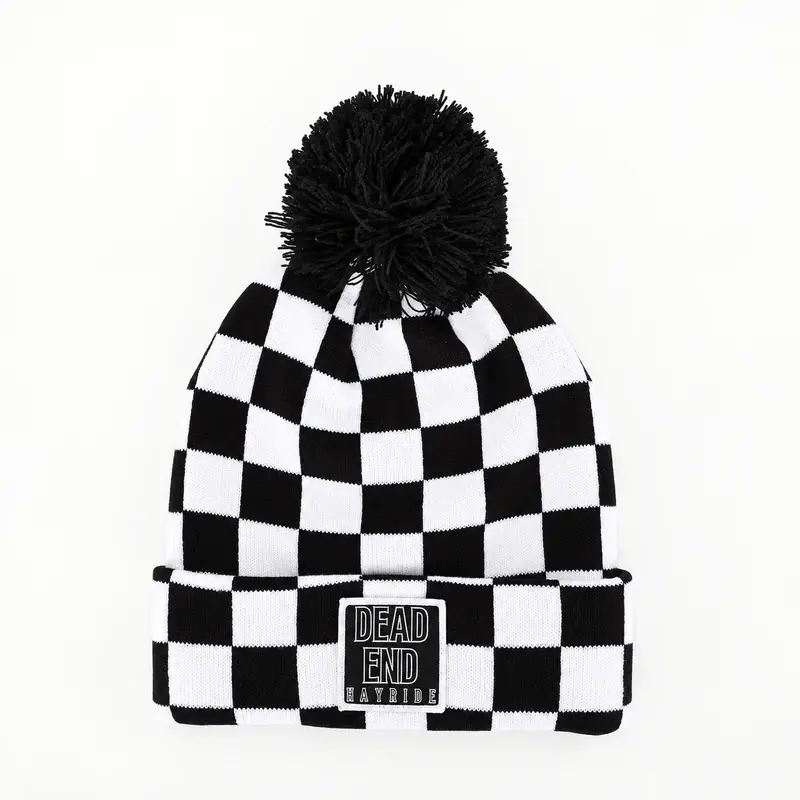 Black-and-white checkerboard jacquard pom-pom beanie with a cuff label