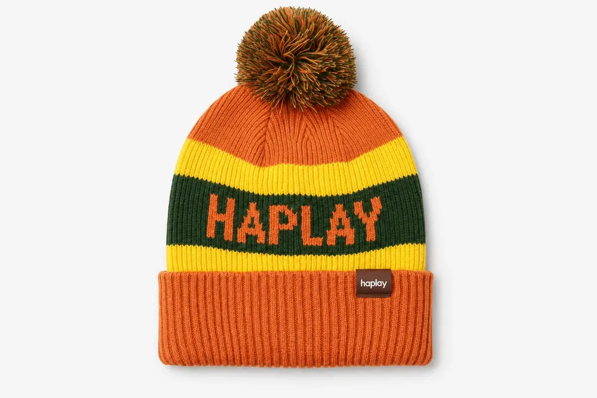 Orange jacquard pom pom beanie with yellow and green stripes and HAPLAY lettering