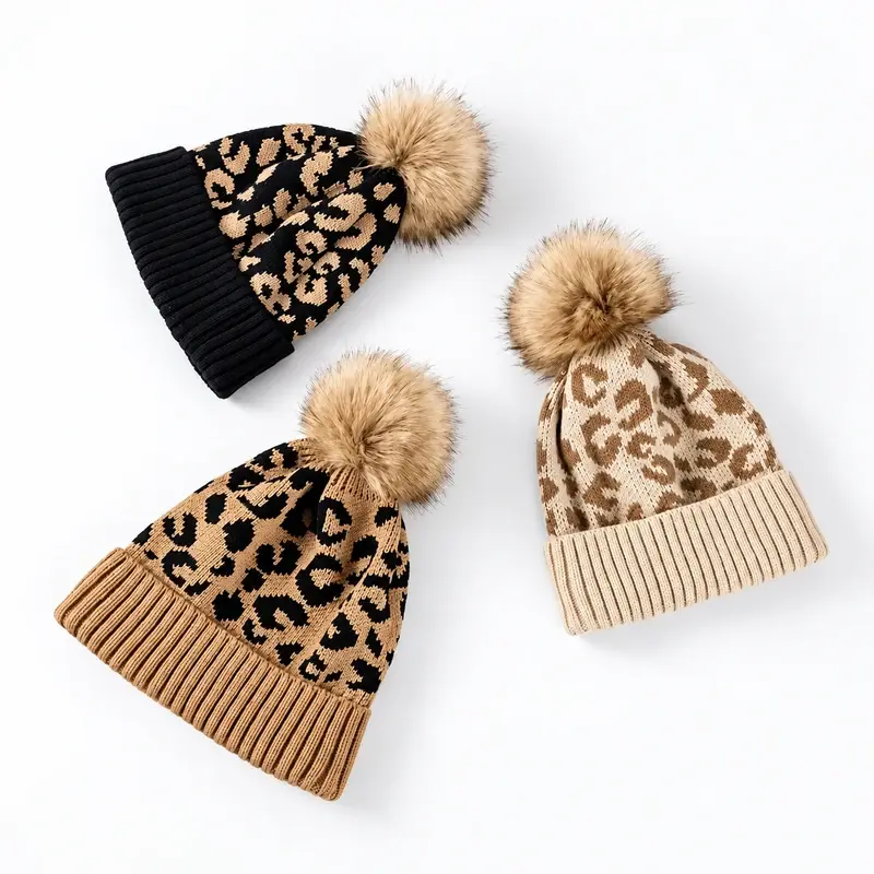 Three leopard jacquard beanies with beige faux fur pom poms