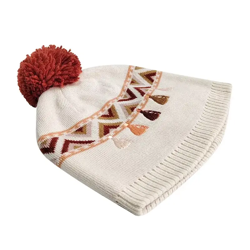 Cream pom pom beanie with red geometric knit pattern
