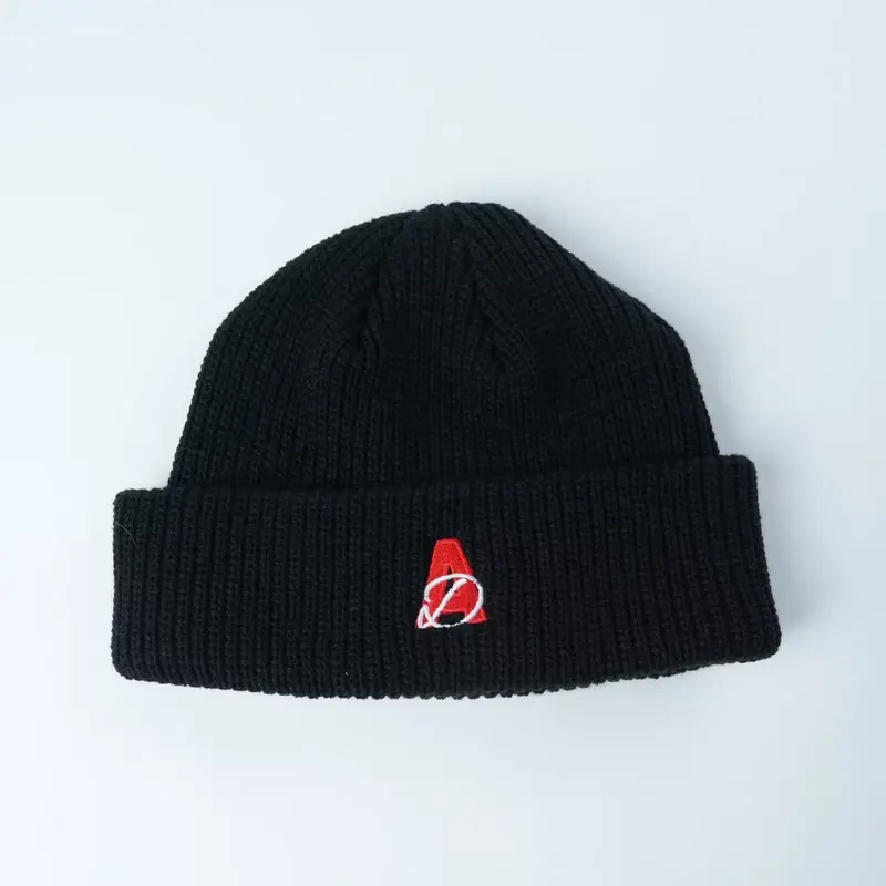 Black rib-knit beanie with a red and white embroidered motif on its cuff