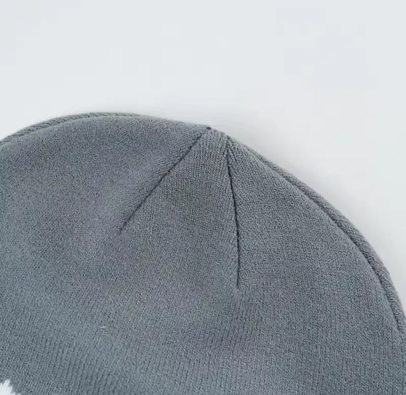 Close-up of a gray knit beanie surface and crown seam