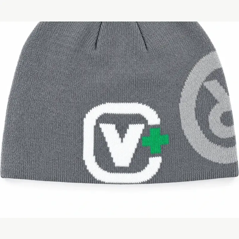 Close view of a white knit mark on a gray cuffless beanie