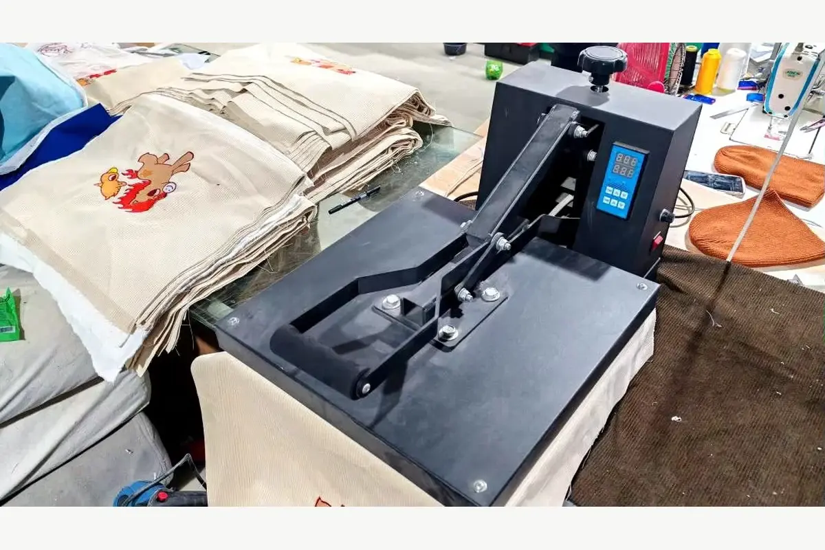Heat press equipment and textile pieces on a factory worktable