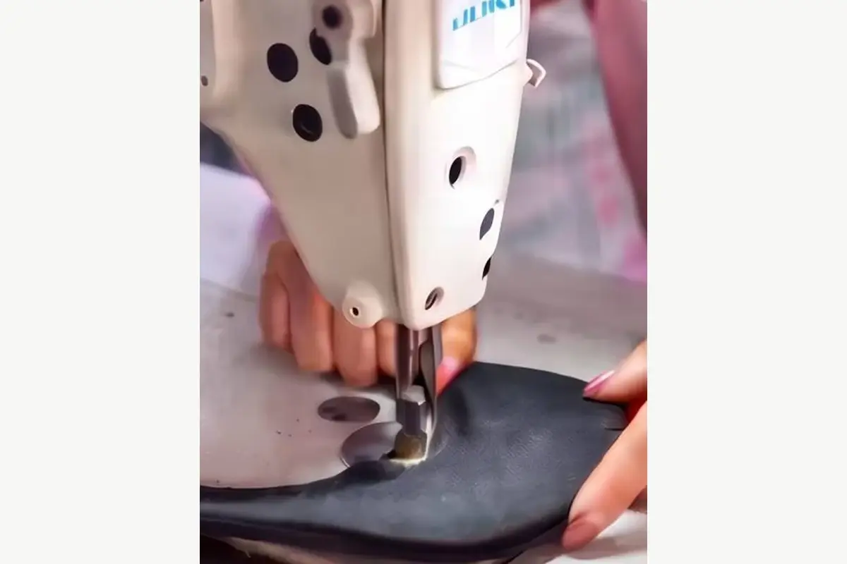 Worker sewing fabric at a production machine