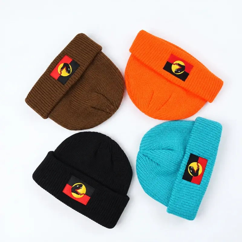 Four ribbed cuffed beanies in brown, orange, black and turquoise, each displaying a patch