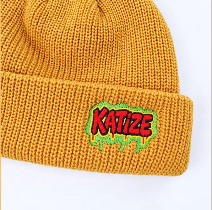 Close view of a yellow short beanie cuff with a centered multicolor patch