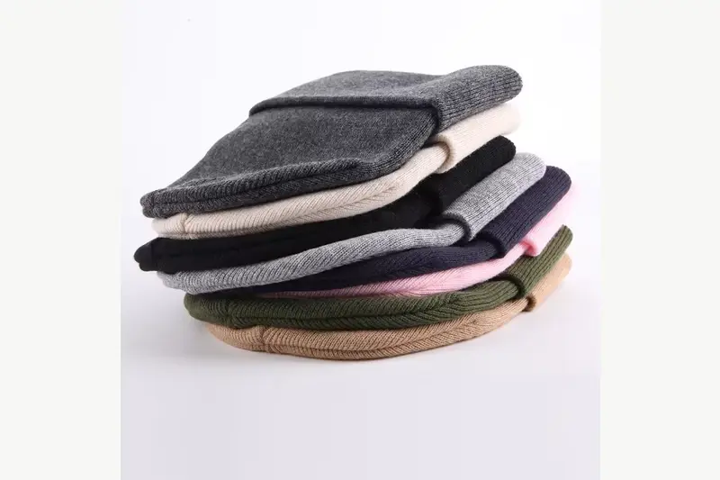 Folded rib-knit cuffed beanies stacked in neutral and pastel colors