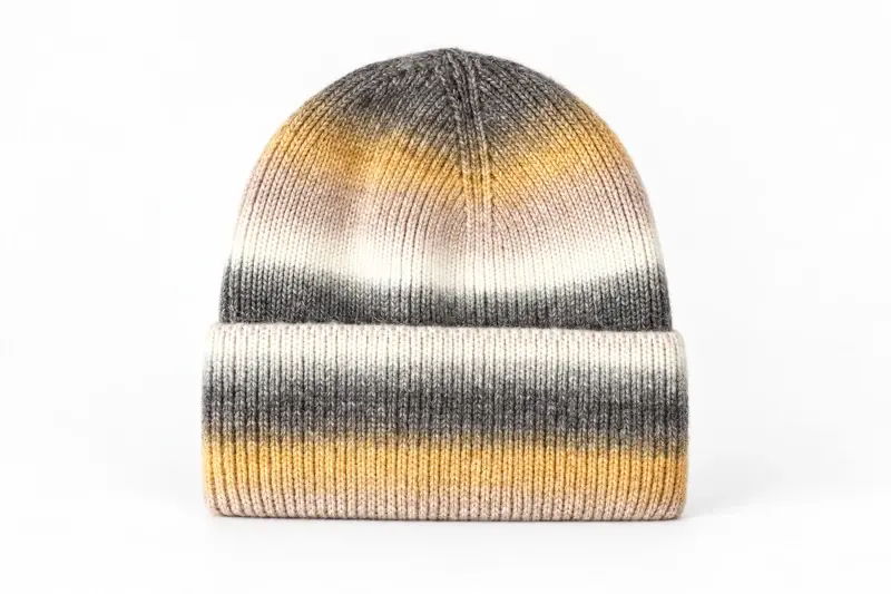 Rib-knit beanie with a visible folded cuff and textured yarn in gray, cream and muted yellow