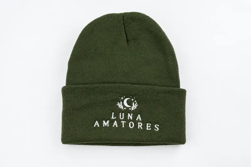 Green ribbed cuffed beanie with white Luna Amatores embroidery, shown as a finished sample