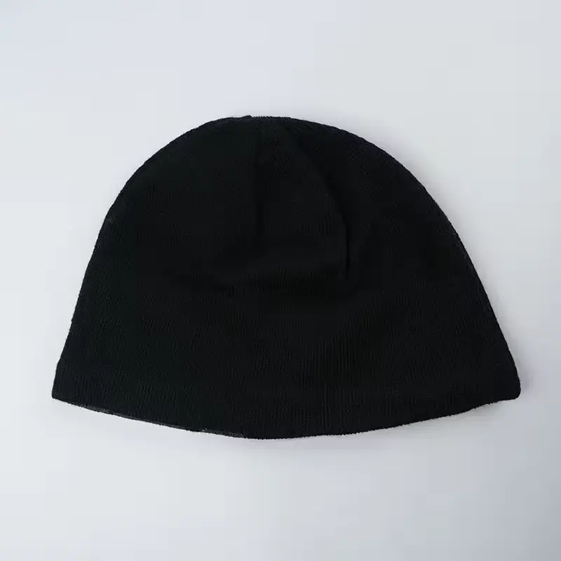 Plain black cuffless beanie laid flat to show its finished shape