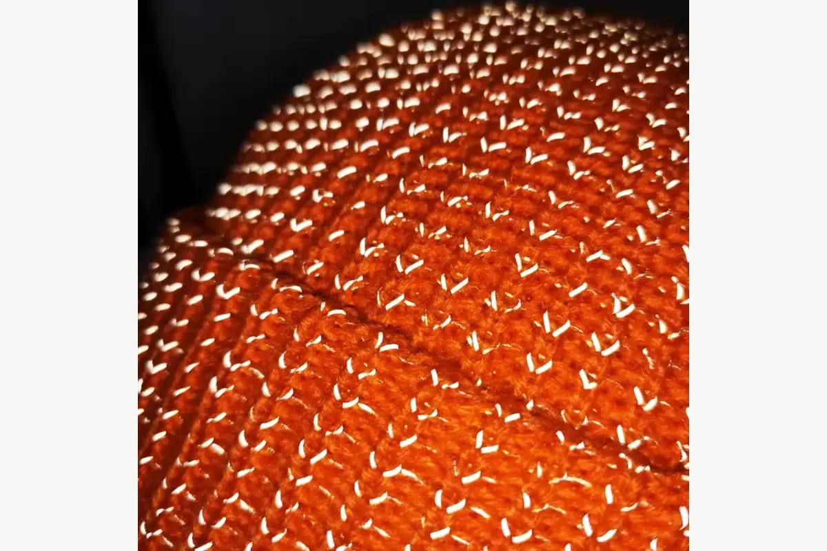 Close view of textured orange knit fabric and yarn loops