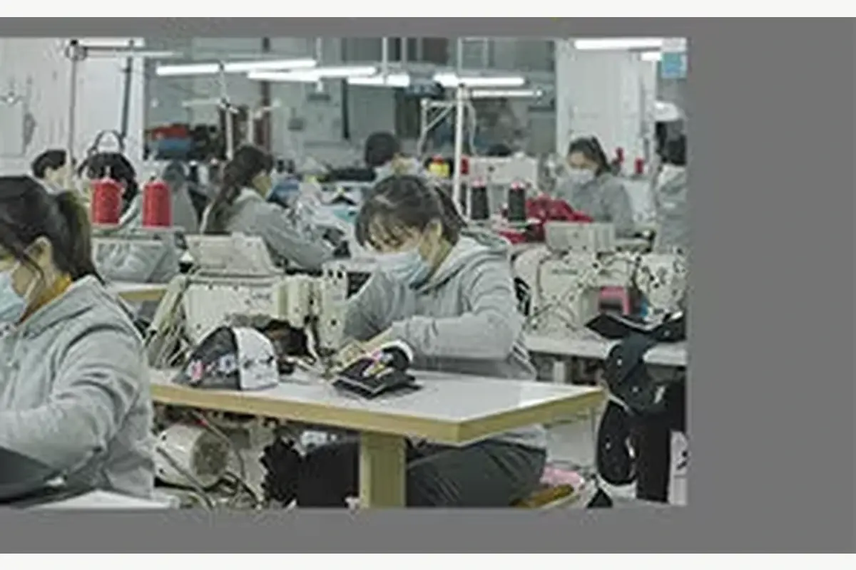 View of textile production equipment and workers in a factory