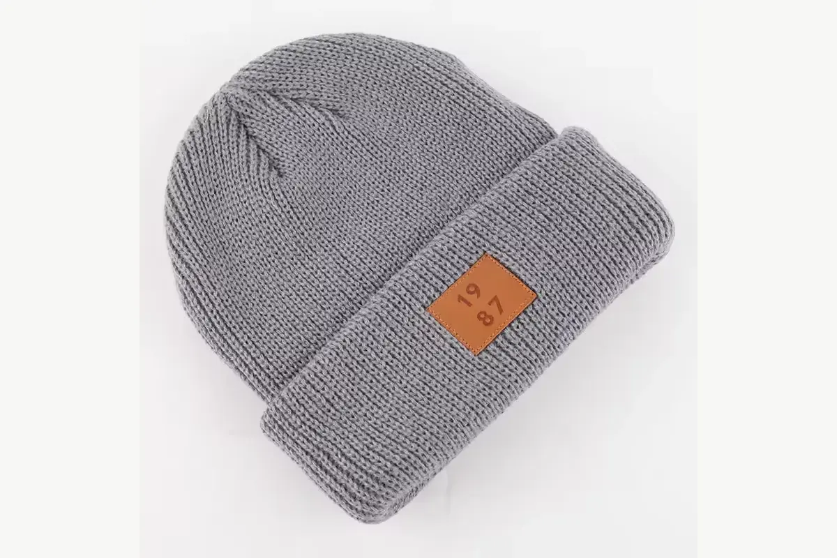 Gray ribbed beanie with a small tan patch on its folded front