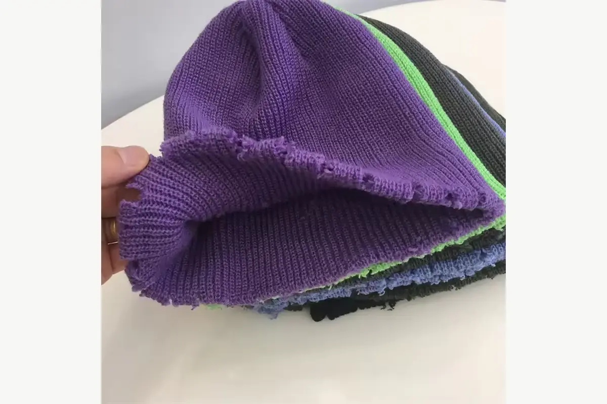 Close view of purple ribbed knit beanie fabric and crown construction