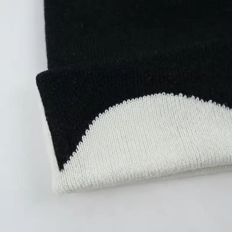 Close view of a black and cream knit cap lower edge and label