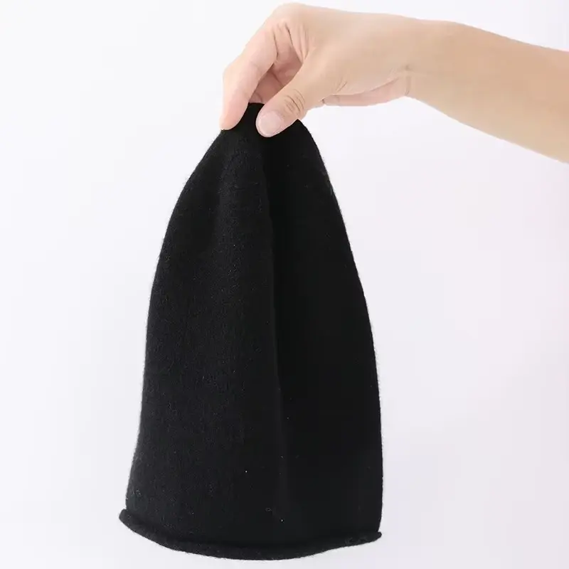 Black lightweight knit cap held upright to show its finished length