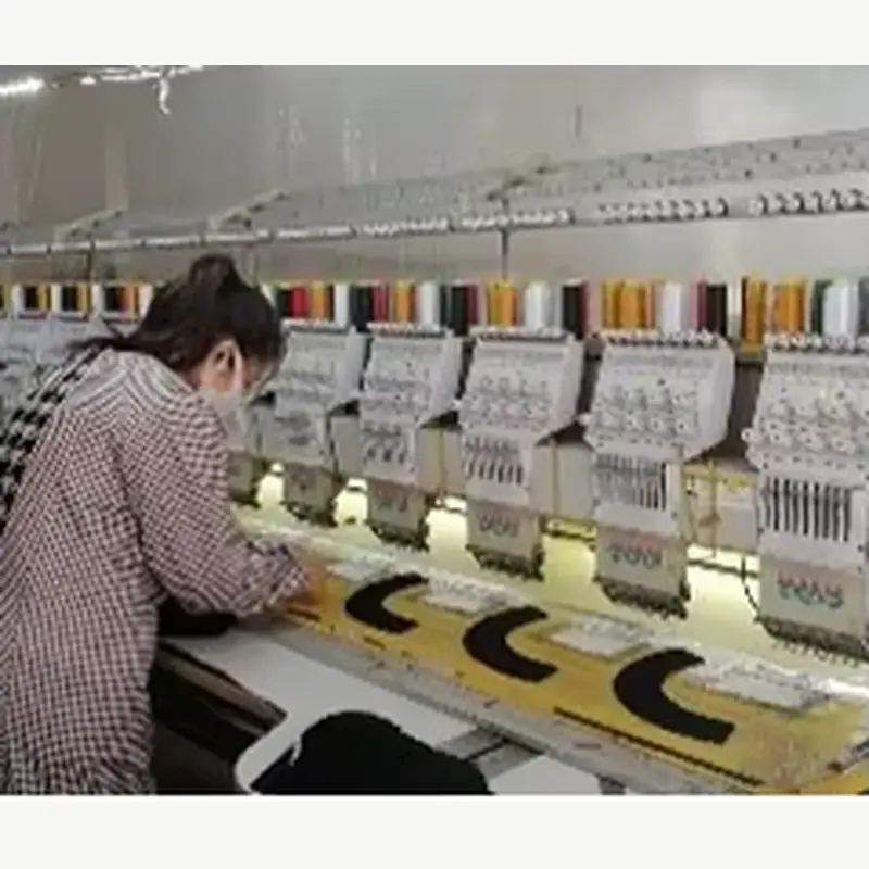 Worker operating textile embroidery machines in a production workshop