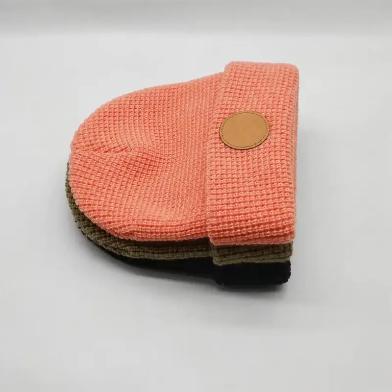 Coral waffle-knit cuffed beanie shown from the side with a plain round patch