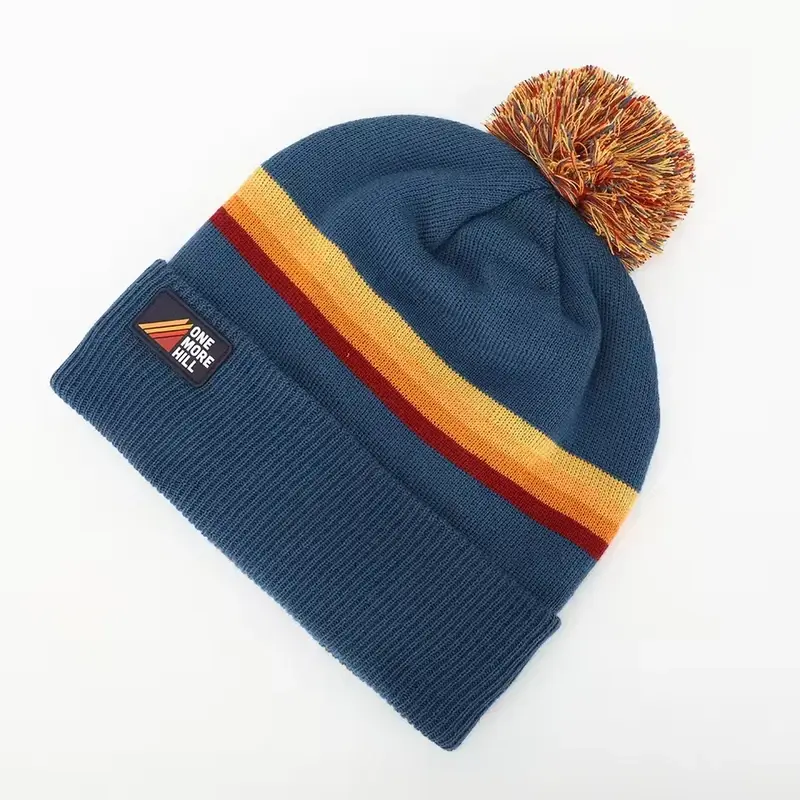 Side view of a blue pom beanie with orange and yellow stripes