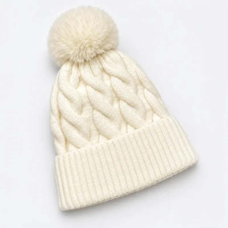 Cream cable-knit beanie with a matching pom-pom